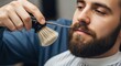 © Valfiyy - Barber trimming beard and mustache with scissors and brush, close-up shot