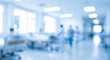 © birulaut - A blurred view of a hospital corridor with medical staff in the background, showcasing an atmosphere of care and medical professionalism in a healthcare setting.