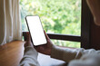 © Farknot Architect - Mockup image of a woman holding mobile phone with blank white desktop screen at home
