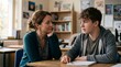© Alva - Adult woman and teenage boy having a serious conversation at a desk in a classroom setting.