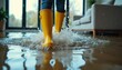 © Vadym - Person wearing yellow boots walks through flood water inside modern home. Water damage spreads across floor, creating large splashes. Furniture is visible in background suggesting indoor setting.