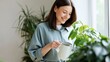 © Mary - Woman watering houseplant at home with watering can