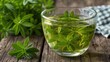 © Ze - Woodruff leaves floating in herbal tea on a wooden table with natural green tones.