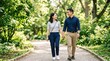 © MuzammilZia - Happy young East Asian couple walking hand in hand on a scenic path in a lush green park, smiling and looking at each other