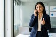 © Asier - Professional woman communicating on phone, showing success gesture in modern office