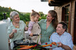 © Halfpoint - Multi generation family grilling outside on patio in summer during garden party