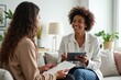 © YouraPechkin - Two smiling women discussing documents and technology in a modern office lounge