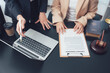 © Wicitr - Legal Consultation: Two individuals are reviewing a contract at a desk, with a laptop, gavel, and law book in view, signifying a legal discussion and contract agreement.
