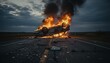 © artvibi - A burning car overturned in the middle of a road at twilight with debris scattered across the asphalt.