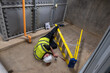 © RCH Photographic - Mature maintenance engineer wearing a hard hat has fallen off his ladder and is lying on the floor injured. Slips, trips, and falls at work affect health and safety in the workplace