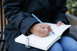 © Oleksii Syrotkin/Stocksy - Cropped black businesswoman writing in notebook on bench outdoors