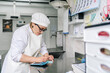 © Daniel Gonzalez/Stocksy - Female artisan cheesemaker calculating expenses in dairy factory