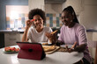 © Niyaz Tavkaev/Stocksy - Diverse Multiracial women chatting online while sharing pizza at home