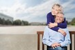 © BillionPhotos.com - Senior couple smiling while woman embraces man on a bench in a city square