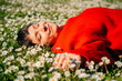 © Maria Sher/Stocksy - Person Relaxes on Grass Among White Flowers in Bright Red Sweater