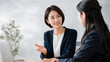 © Yka - 会議室で同僚に説明する女性ビジネスパーソン