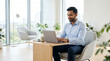© akridiy - Indian businessman working on laptop in bright modern office