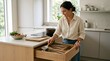 © Pangastuti - Woman arranging cutlery in modern kitchen drawer