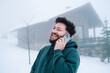 © Igor/Stocksy - Smiling man talking on smartphone outside snowy mountain cabin