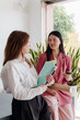 © Lucas Ottone/Stocksy - Young professional women at work having a conversation inside office