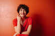 © Ani Dimi/Stocksy - Young woman portrait over red background.