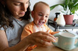 © Raul Navarro/Stocksy - Mother and toddler laughing enjoying messy milk moment