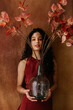 © Tania Cervian/Stocksy - Woman holding large glass vase with autumn leaves