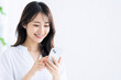 © maaagram - 笑顔でスマートフォンを操作する若い日本人女性 Generative AI