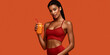 © S-DESIGN - A fit woman in red sportswear poses confidently, holding a refreshing orange juice. Her dark hair is styled in braids, and she looks directly at the camera with a slight smile