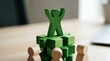 © AspctStyle - Green wooden figure standing on puzzle piece stack with arms raised for leadership achievement and business team success on office desk