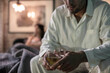 © Westend61 - Man sitting on bed having a drink