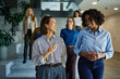 © bernardbodo - Diverse businesswomen walking and talking in office hallway