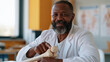 © Katerina Bond - Male osteopathic surgeon in a white coat explains a diagnosis to a patient while holding a human bone model at his office desk.