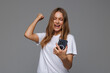 © F8  \ Suport Ukraine - Excited woman using mobile phone, celebrating online win isolated on gray