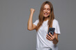 © F8  \ Suport Ukraine - Excited woman using mobile phone, celebrating online win isolated on gray