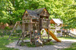 © Anastasiia - Wooden playhouse with slide and climbing wall in park on sunny day