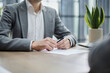 © ASDF - Man in grey blazer signs document at wooden desk