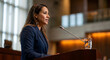 © David Martínez - Mujer profesional dando un discurso en un podio con micrófono durante una conferencia o debate político
