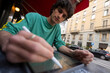© Mattia/Stocksy - Young man sits at cafe table while using tablet in Italy