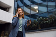 © Novak - Confident businesswoman standing outside a modern glass office building and talking on a smartphone