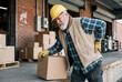 © Meow Creations - Senior warehouse worker suffering from back pain while lifting box