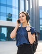 © Es - Young woman in blue shirt talking on phone outside modern building