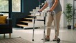 © Lisicus - Senior woman using a rolling walker frame for mobility support in a bright living room. Elderly lady rehabilitation and health care concept for nursing home or independent living