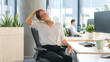 © Artyom - Office worker woman stretching her neck at a desk in a bright modern open-plan workspace