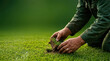 © Nakarin - Groundskeeper hands holding turf with soil on green grass field in natural light