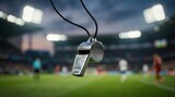 Shiny metal referee whistle suspended over blurred stadium pitch during professional soccer match
