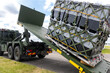 © Kyryl Gorlov - Military hook-lift truck unloads cargo pallet secured netting loading ramp airfield. Airforce logistics operation transport, deployment readiness, mobility support and defense infrastructure