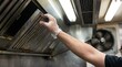 © Yasmin - Maintenance worker removing a greasy commercial kitchen exhaust hood filter for cleaning.