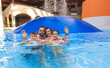 © leszekglasner - Happy family portrait smiling and waving hands in an indoor swimming pool with water mushroom fountain at a water park