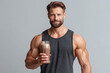 © JoeyMarut - Fit man holding protein shake in mason jar smiling after workout, muscular torso in tank top, healthy active lifestyle and fitness nutrition